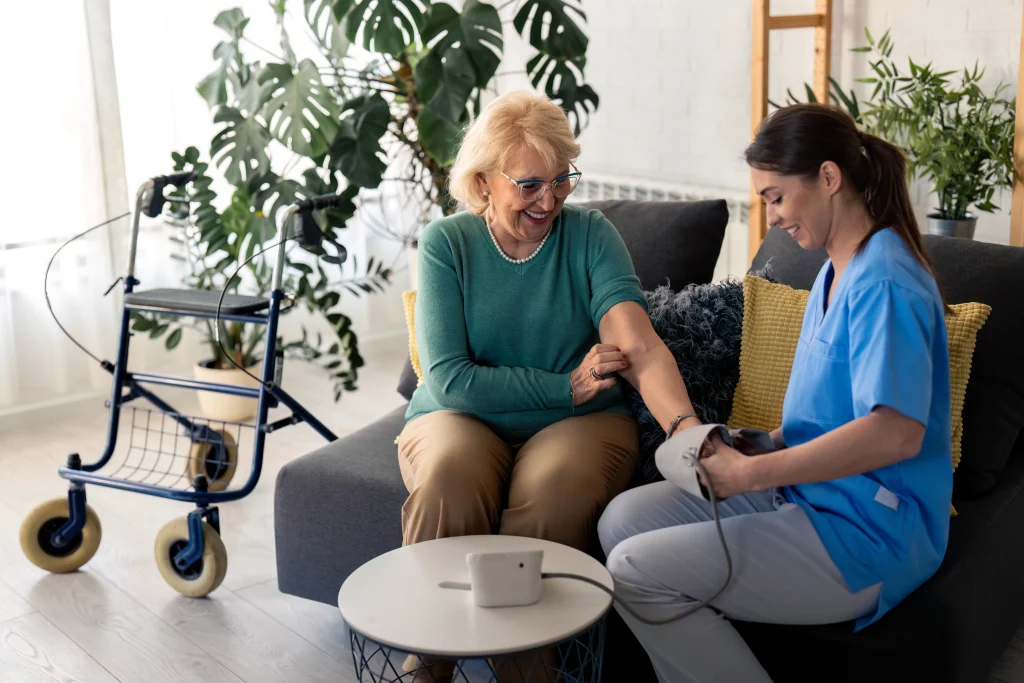 Hauskrankenpflege. Krankenschwester misst Patientin den Blutdruck zu Hause auf dem Sofa