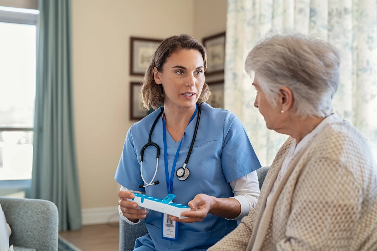Medizinische Hauskrankenpflege. Krankenschwester reicht Patientin Medikamente