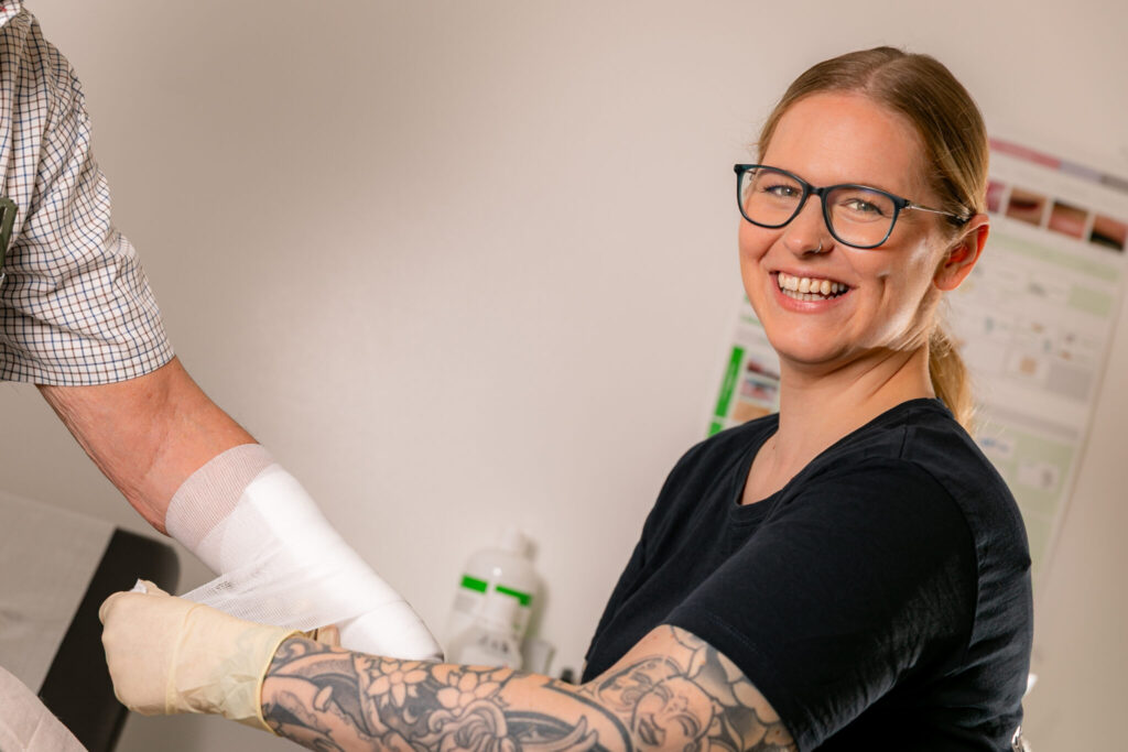 Wundmanagerin während eines Verbandwechsels am Unterarm