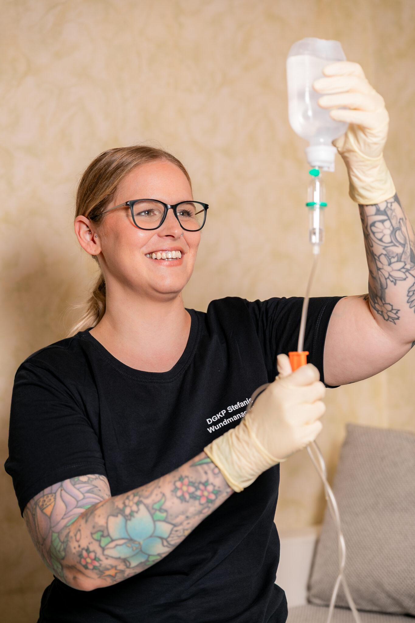 Krankenschwester bei dem Herrichten einer Infusion bei einer Patientin zu Hause