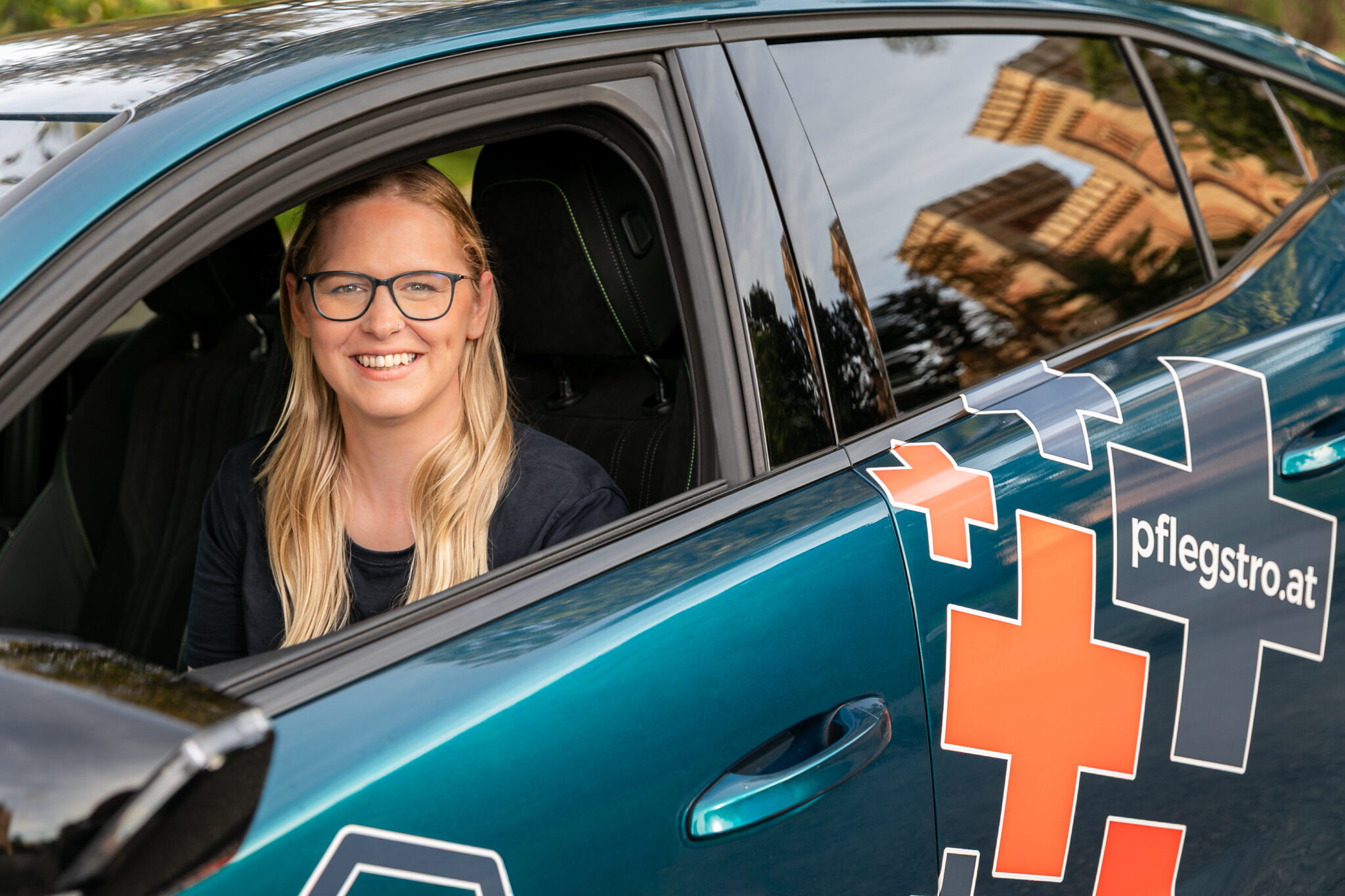 Krankenpflegerin Stefanie lächelnd sitzend im Dienstauto